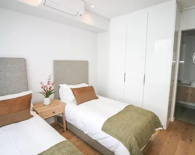 two beds in a room with white walls at Charming Apartment in Cape Winelands District in Stellenbosch