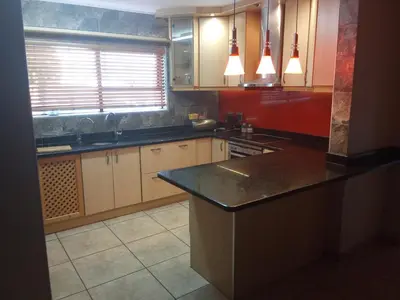 a kitchen with wooden cabinets and a black counter top at Schubert Self Catering Accomodation in Brackenfell