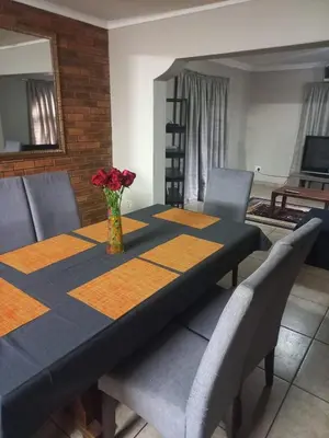 a dining room table with a vase of flowers on it at Schubert Self Catering Accomodation in Brackenfell