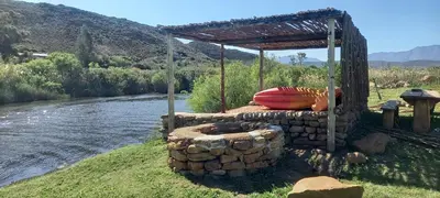 a structure with a fire pit next to a river at Rivergrace Farm in Robertson
