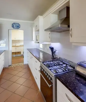 a kitchen with white cabinets and a stove top oven at Skye Cottage in Onrus River in Hermanus