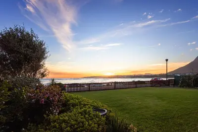 a view of the ocean at sunset from a yard at Skye Cottage in Onrus River in Hermanus