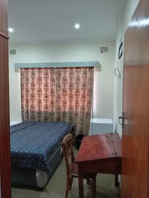 a small bedroom with a bed and a table at Beyond Expectation in Avondale