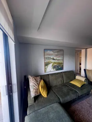 a living room with a green couch with yellow pillows at Cosy Flat Steps from the Beach in Cape Town