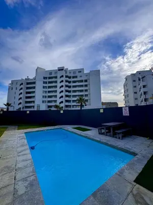 a large blue swimming pool in front of a building at Cosy Flat Steps from the Beach in Cape Town