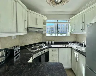 a kitchen with white cabinets and a stove and a window at Ocean View in Hermanus