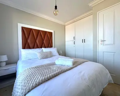 a bedroom with a large white bed with a headboard at Ocean View in Hermanus