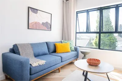 a blue couch in a living room with a window at Paarl Superior Studio 231 - With Onsite Parking & Comforts in Paarl