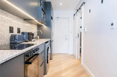 a kitchen with blue cabinets and a wooden floor at Paarl Superior Studio 231 - With Onsite Parking & Comforts in Paarl