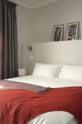 a bedroom with a bed with a red blanket on it at Modern Family Golf Lodge in Winelands Paradise in Paarl