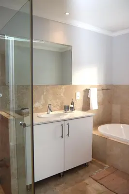a bathroom with a white sink and a tub at Modern Family Golf Lodge in Winelands Paradise in Paarl