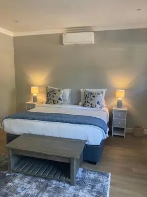 a bedroom with a bed with two tables and two lamps at Villa 121 Franschhoek Lermitage in Franschhoek