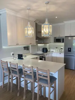 a kitchen with white cabinets and a table with chairs at Villa 121 Franschhoek Lermitage in Franschhoek
