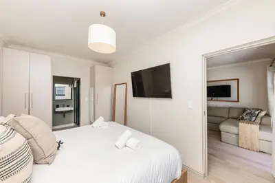 a bedroom with a white bed and a couch at Cape On Viola 13-Blouberg Gem Walk to Kite Beach & Ocean Views in Cape Town