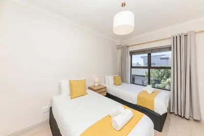 two beds in a room with a window at Cape On Viola 13-Blouberg Gem Walk to Kite Beach & Ocean Views in Cape Town
