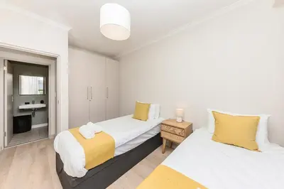a bedroom with two beds with yellow and white at Cape On Viola 13-Blouberg Gem Walk to Kite Beach & Ocean Views in Cape Town