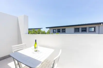 a bottle of wine sitting on a table on a balcony at Cape On Viola 13-Blouberg Gem Walk to Kite Beach & Ocean Views in Cape Town