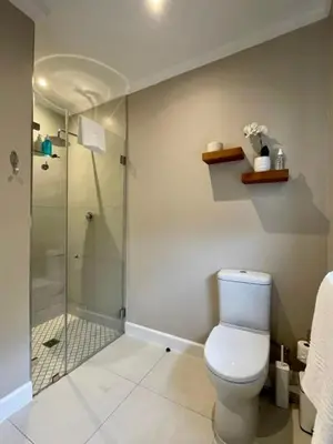 a bathroom with a toilet and a glass shower at Villa Mignon in Franschhoek