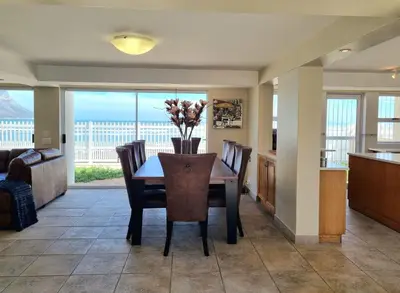 a kitchen and dining room with a table and chairs at Paradise Tide - 4 Bedroom Beachfront home with Private Pool in Cape Town