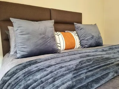 a bed with grey pillows and a brown headboard at Paradise Tide - 4 Bedroom Beachfront home with Private Pool in Cape Town