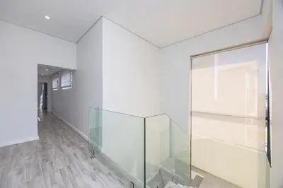 a glass elevator in a white room with wooden floors at Cape Town Bliss in Sandown in Cape Town