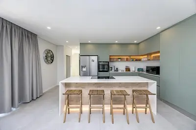 a kitchen with a counter with four chairs around it at Cape Town Bliss in Sandown in Cape Town