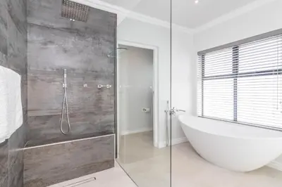 a bathroom with a tub and a glass shower at Executive 1 bedroom Cottage, with aircon, king size bed and modern bathroom in Hermanus
