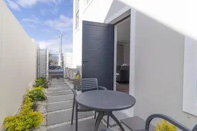 a patio with a table and chairs on a balcony at Executive 1 bedroom Cottage, with aircon, king size bed and modern bathroom in Hermanus
