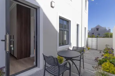 a small patio with a table and chairs on a balcony at Executive 1 bedroom Cottage, with aircon, king size bed and modern bathroom in Hermanus