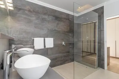 a bathroom with a toilet and a glass shower at Relax in comfort and style with a swimming pool, aircons and braai room in Hermanus