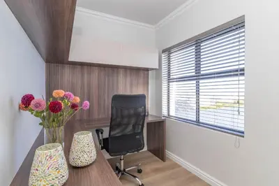 a office with a desk and a chair and flowers at Relax in comfort and style with a swimming pool, aircons and braai room in Hermanus