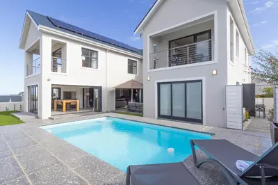 a house with a swimming pool in front of it at Relax in comfort and style with a swimming pool, aircons and braai room in Hermanus