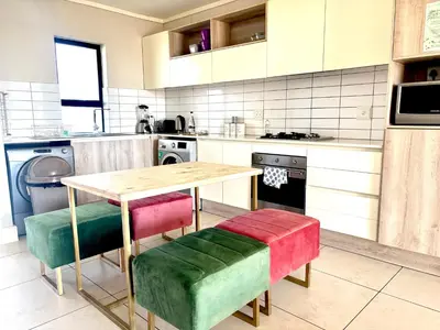 a kitchen with a wooden table and colorful chairs at Luxe watersedge apartment in Cape Town