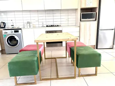 a kitchen with a table and two green stools at Luxe watersedge apartment in Cape Town