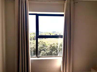 a window with curtains in a room with trees at Luxe watersedge apartment in Cape Town