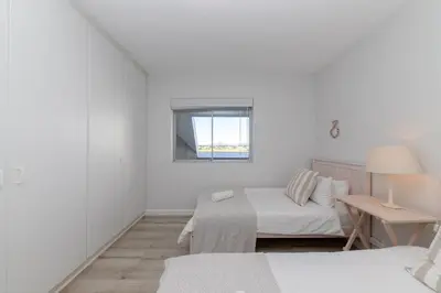 a white room with a bed and a window at Dolphin Beach C110 Beachfront Beauty in Cape Town