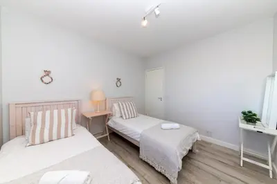 a bedroom with two beds and a table with a lamp at Dolphin Beach C110 Beachfront Beauty in Cape Town