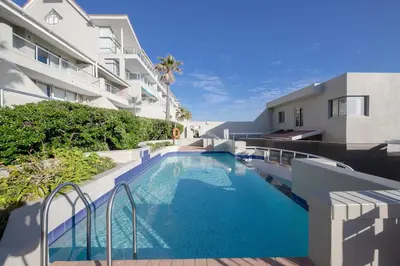 a swimming pool in front of a building at Dolphin Beach C110 Beachfront Beauty in Cape Town