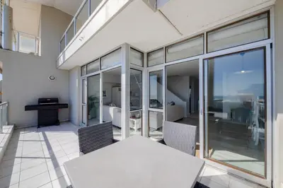 a dining room with a table and some glass doors at Dolphin Beach C110 Beachfront Beauty in Cape Town