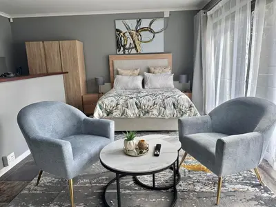 a bedroom with a bed and two chairs and a table at Apartment in Bellville - self-catering in Bellville
