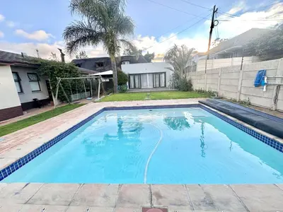 a large blue swimming pool in front of a house at Apartment in Bellville - self-catering in Bellville