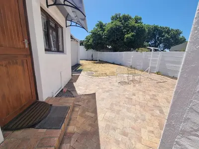 a house with a yard with a fence and a door at Peaceful, Cheerful, Family Friendly 3Bedroom house in Edgemead