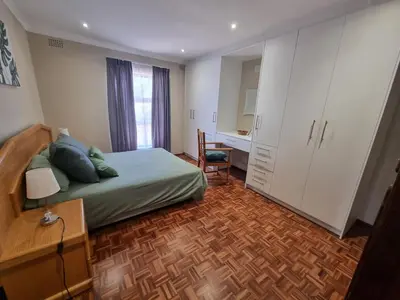 a bedroom with a bed and a desk in it at Peaceful, Cheerful, Family Friendly 3Bedroom house in Edgemead