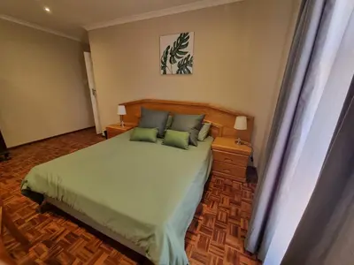 a bedroom with a bed with green sheets and pillows at Peaceful, Cheerful, Family Friendly 3Bedroom house in Edgemead