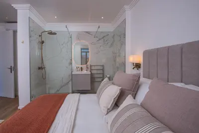 a bedroom with a king sized bed and a shower at De Waal Grandeur Apartment in Stellenbosch