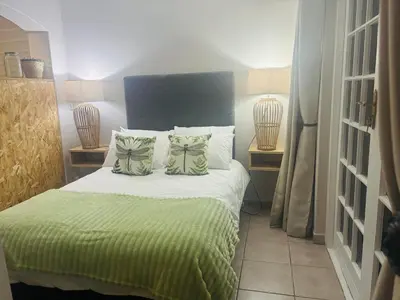 a bedroom with a bed with green sheets and pillows at The Dragonfly in Paarl