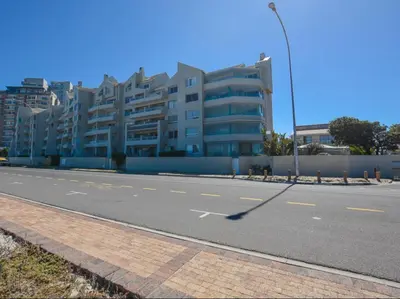an empty street in front of a large building at Cape Town Beachfront Accommodation in Blouberg in Bloubergstrand