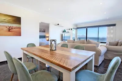 a living room with a table and chairs at Cap Du Mont Cape Town in Bloubergstrand