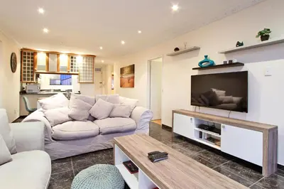 a living room with a white couch and a tv at Cap Du Mont Cape Town in Bloubergstrand
