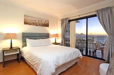 a bedroom with a bed and a large window at Cap Du Mont Cape Town in Bloubergstrand